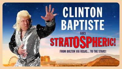 COmedian and clairvoyant Clinton Baptiste wears a silver jumpsuit as he stands against a Las Vagas backdrop. 