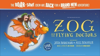 Childrens character Zog flies across a bright blue background with two people sitting on his back 