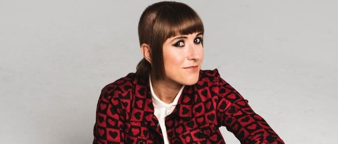 A close up of comedian Maisie Adam against a grey backdrop. 