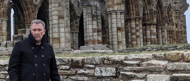 Actor James Gaddass stands in front of the ruins at Whitby Abbey