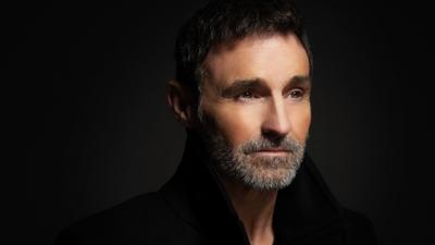 A headshot of actor Marti Pellow against a black backdrop. 