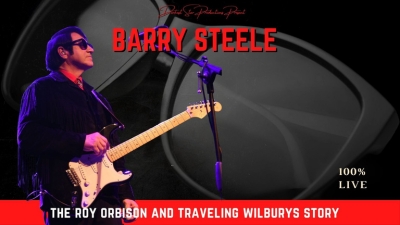 Barry Steele as Roy Orbison playing a guitar againt a black backdrop.