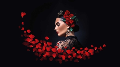 A dark background with a dark haired lady with red roses in her hair. 