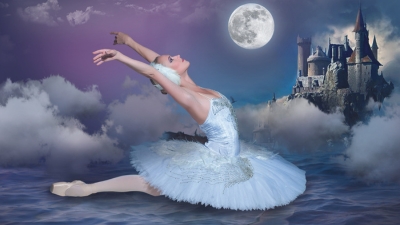 A ballet dancer in white dances in front of a moonlit backdrop.
