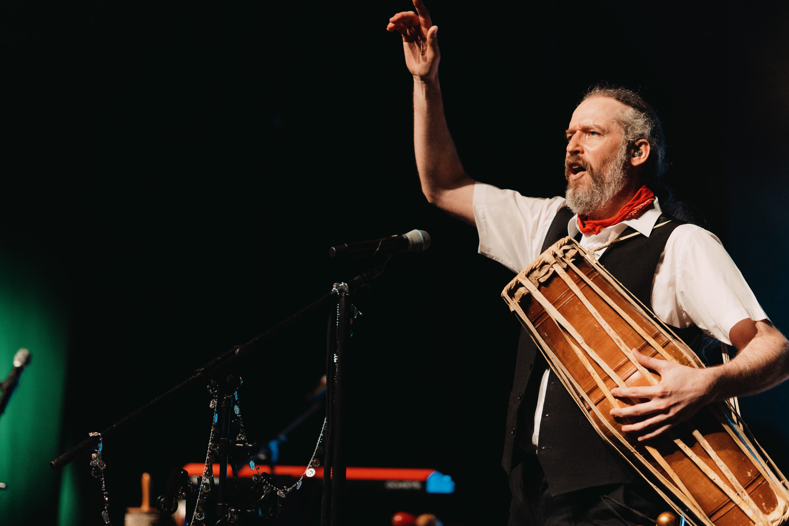 A member of The Fleetwood Mac Legacy plays a wooden instrument on stage. 