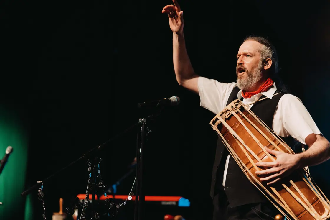A member of The Fleetwood Mac Legacy plays a wooden instrument on stage. 